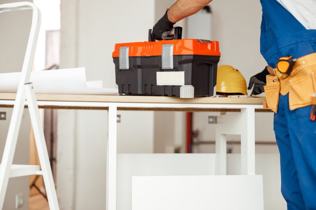 Cropped shot of contractor worker in overalls putting toolbox on the table, ready for construction