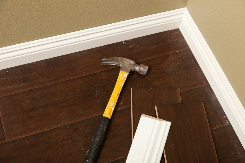 Hammer, Laminate Flooring and New Baseboard Molding Abstract.