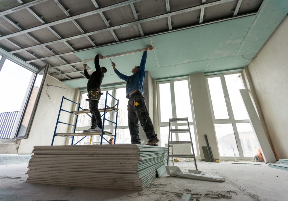 Construction worker assemble a suspended ceiling with drywall and fixing the drywall to the ceiling